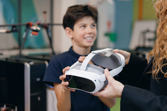 Smiling boy accepting vr headset from instructor, technology science