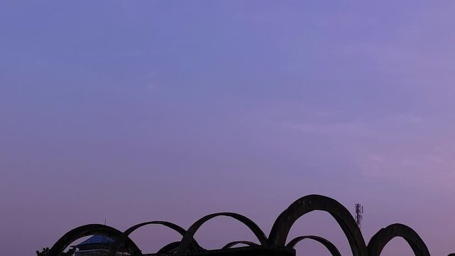 Minimalist silhouette of curved architectural arches against a soft purple twilight sky, representing urban cityscape aesthetics, serene evening atmosphere, and geometric background with large copy sp