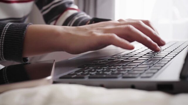Close-up zoom in shot of a finger pressing a laptop keyboard key, conveying typing, digital communication and focused office work.