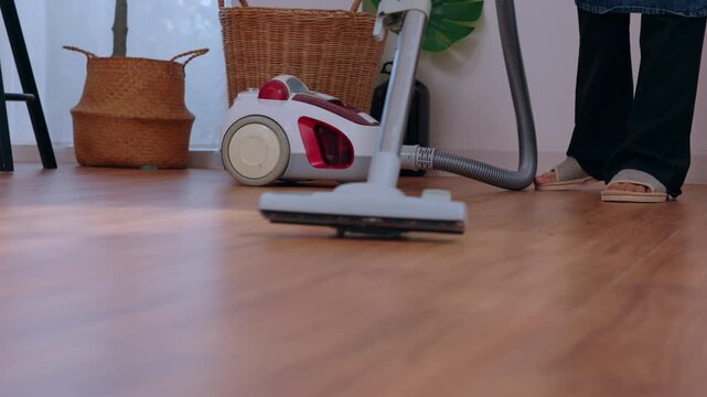 Vacuum cleaner floor cleaning home housework appliance person hardwood interior hose nozzle on wood surface in cozy indoor room with basket plant decor tidy domestic chore