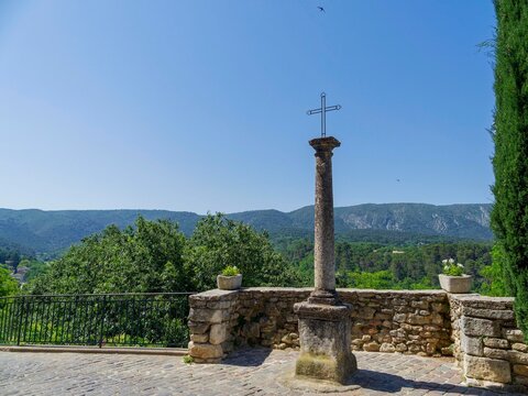 M&eacute;nerbes in Vaucluse. Church Street at the top of the Citadel. An iron cross fixed to a square base of osl limestone stands facing the Luberon mountains and verdant state forest