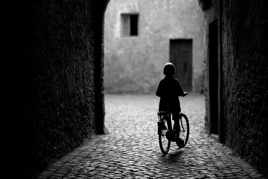 Solo cyclist in silhouette at the end of a historic cobblestone alley
