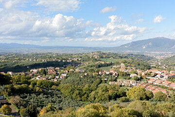 Fototapeta premium Panoramic view of the Umbrian countryside and hills from the historic stone village with olive groves, rural houses, mountains, and a cloudy blue sky