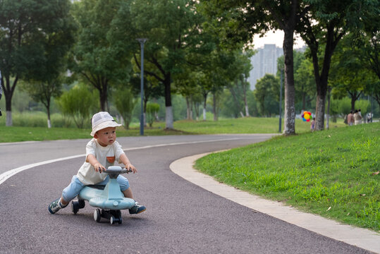 Asian toddler riding wiggle car on park path