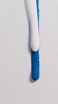 Vertical white blue paint dripping down white textured paper background