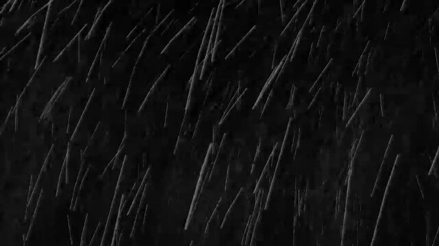 Rain streaks descend across a dark surface creating a dramatic and rhythmic visual composition of water.