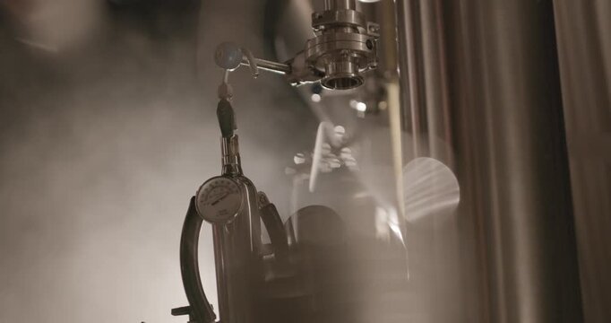 Close up of pressure gauges and stainless steel fermentation tank in modern craft brewery