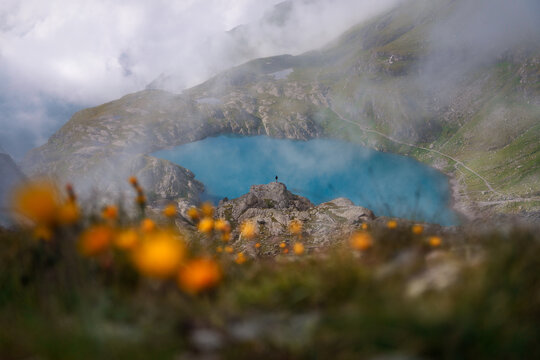 Lone figure above Schottensee lake with wildflowers, Pizol