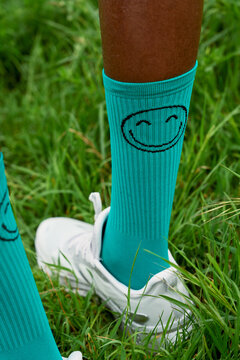 Bright Turquoise Socks With a Smiley Face Design on Grass