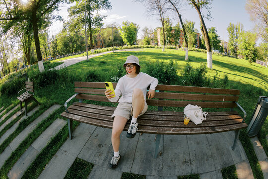 Young Person Relaxes on a Bench in a Park During Sunny Afternoon