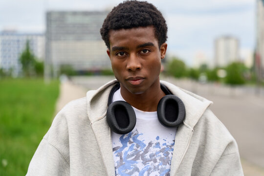 Young Man With Headphones Stands in Urban Setting on a Cloudy Day