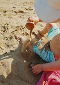 Child Playing in Sand at the Beach With a Cup and Towel