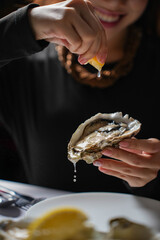 Woman squeezing fresh lemon juice over a raw oyster © udeyismail