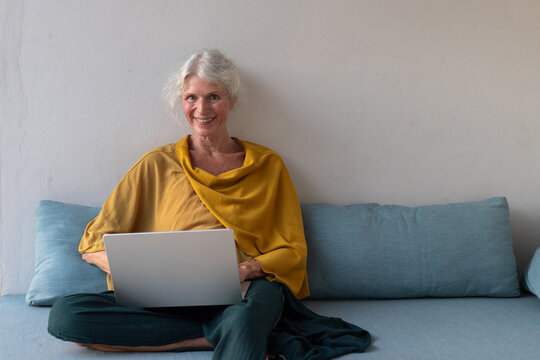 senior woman with laptop, portrait looking at camera and smiling