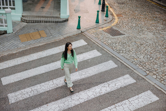 Woman Walking Across Zebra Crossing in Historic Urban Street