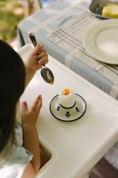 A little girl is eating a soft boiled egg