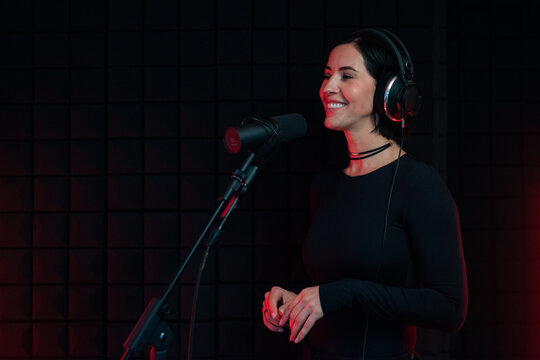 Woman smiling while standing near microphone in studio 