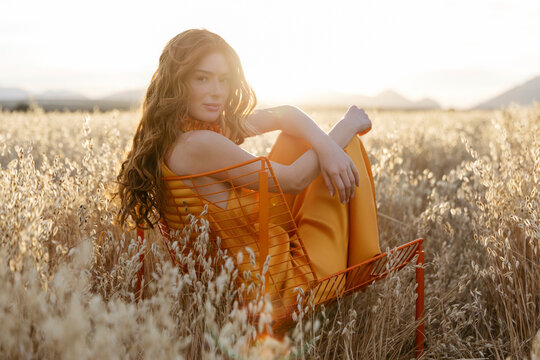 Woman in orange dress sitting in golden field 
