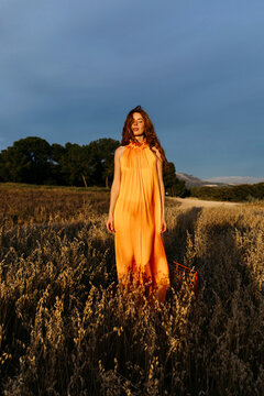 Woman in orange dress standing in golden field