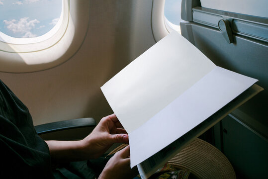 Female is holding a mockup magazine on the plane
