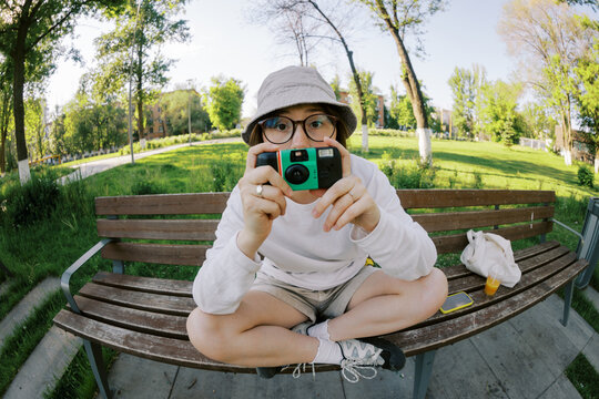Person Sitting on a Bench Holding a Camera in a Park