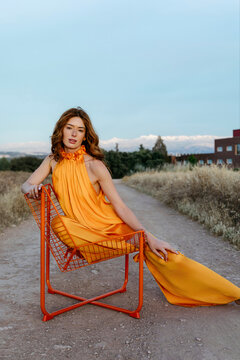 Model posing in orange dress outdoors
