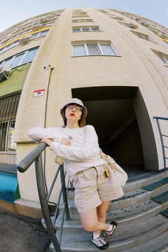 Woman Stands by Building Entrance on a Sunny Day in the City