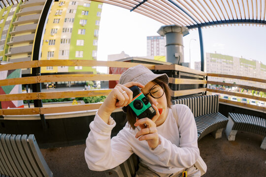 Young Person Takes a Picture With a Camera in the City.