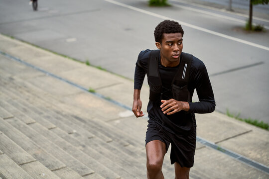 Young Man Runs up Steps in Urban Area During Daytime