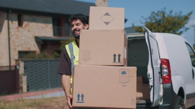 Delivery driver carrying a stack of boxes from a transport van