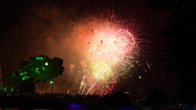 Vibrant fireworks burst over the iconic Dragon Bridge at night, creating a stunning spectacle for crowds along the Han River in Da Nang, Vietnam