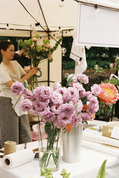 A florist arranges blooms at an outdoor market stall
