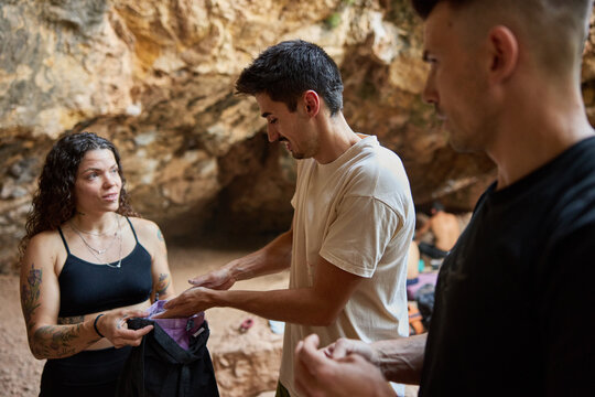 Friends gather inside cave while preparing for climbing session