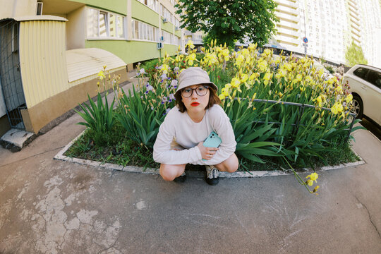 Young Person Sits Near Flowers in Urban Area on a Sunny Day