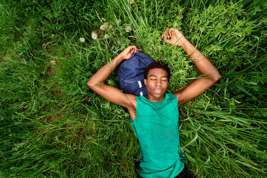 Young Person Lies on Grass During Sunny Day in Park