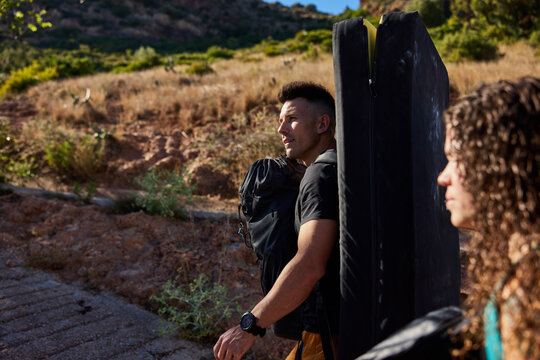 Climbers on a sunlit trail with pads and backpacks