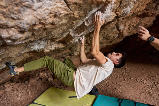 Climber practices bouldering skills in a cave setting during day