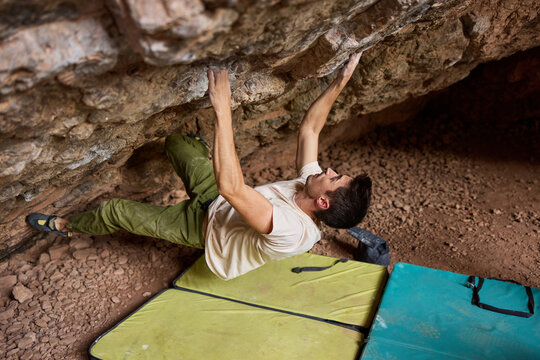 Climber practices bouldering in cave at outdoor climbing site