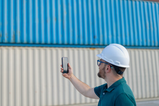 Logistics Supervisor at Container Shipping Yard with smartphone 
