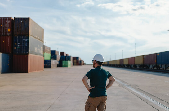 logistics supervisor in a hard hat inspecting a container yard 