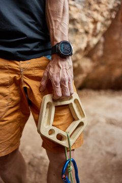 Climber holds training tool in rocky outdoor setting