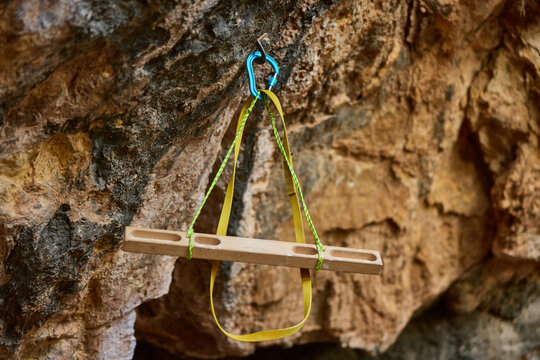Wooden training device hangs from rocky surface for climbing pra