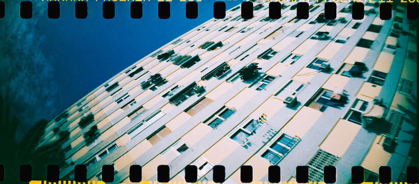 an apartment block rises diagonally in a panoramic image, 35mm film