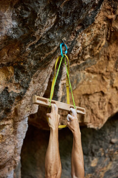 Climber uses wooden board for training grip at rocky location