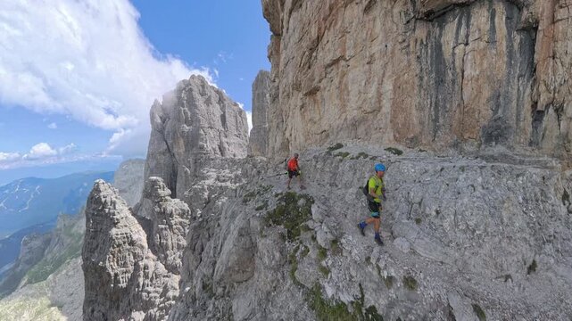 Wide panoramic view of hikers on Via Ferrata Bocchette Centrali below Campanile Alto, Brenta Dolomites