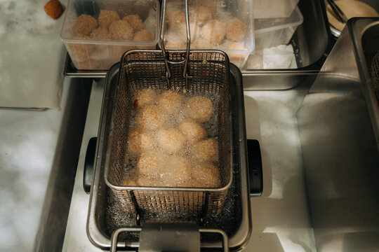 Croquettes frying in deep fryer basket