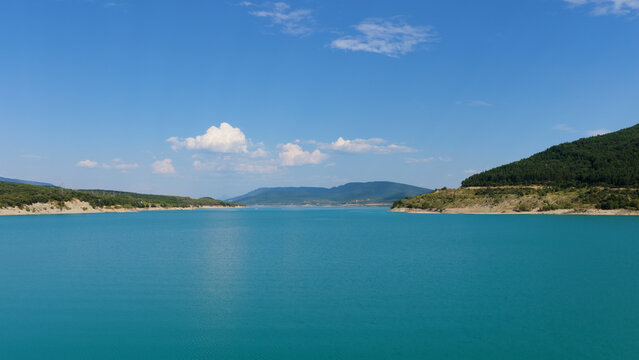 Berdun, Huesca, Spain, Yesa Reservoir featuring still turquoise water surrounded by green hills under a bright blue sky