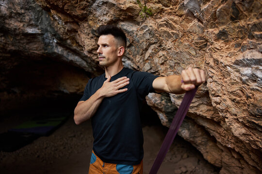 Man stretches in cave before climbing at sunset in nature