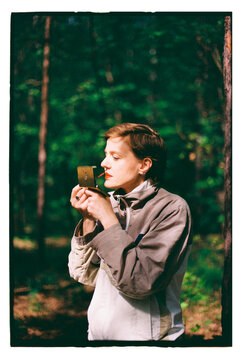 Girl holding a small object in a forest setting during daytime