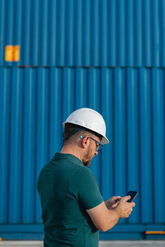 Logistics Supervisor at Container Shipping Yard with smartphone 
